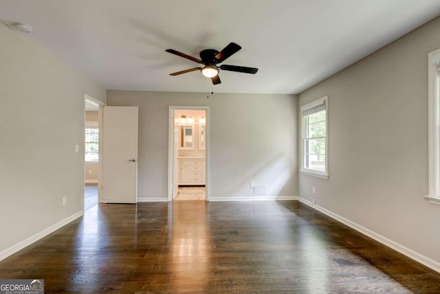 empty room featuring plenty of natural light, a ceiling fan, and wood finished floors