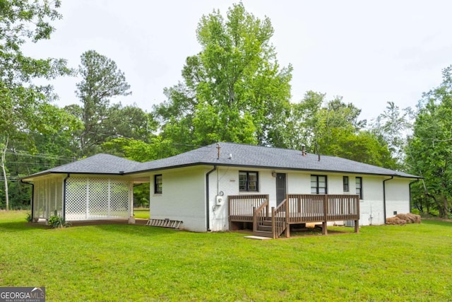 rear view of property with a deck, a yard, and brick siding