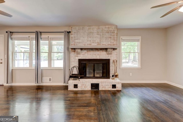 unfurnished living room featuring a ceiling fan, wood finished floors, baseboards, and a brick fireplace