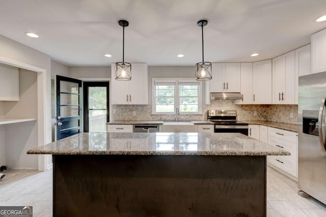 kitchen featuring stainless steel appliances, under cabinet range hood, a sink, white cabinets, and backsplash