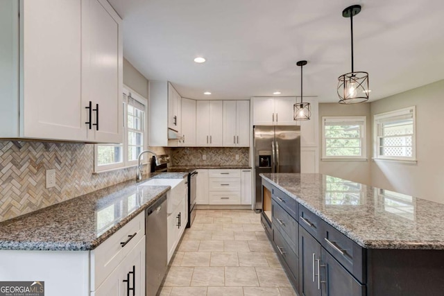 kitchen with appliances with stainless steel finishes, white cabinets, healthy amount of natural light, a kitchen island, and recessed lighting