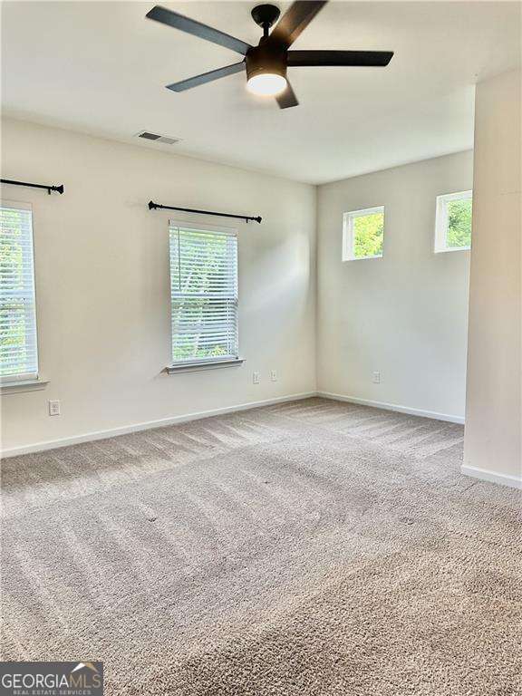 carpeted empty room with a ceiling fan and baseboards