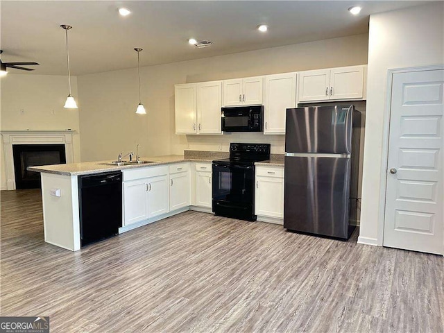 kitchen with black appliances, a sink, open floor plan, white cabinetry, and recessed lighting