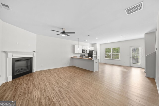 235 Centennial Cir, Canton, GA 30114 - kitchen with black microwave, light wood-style floors, stove, baseboards, and a peninsula