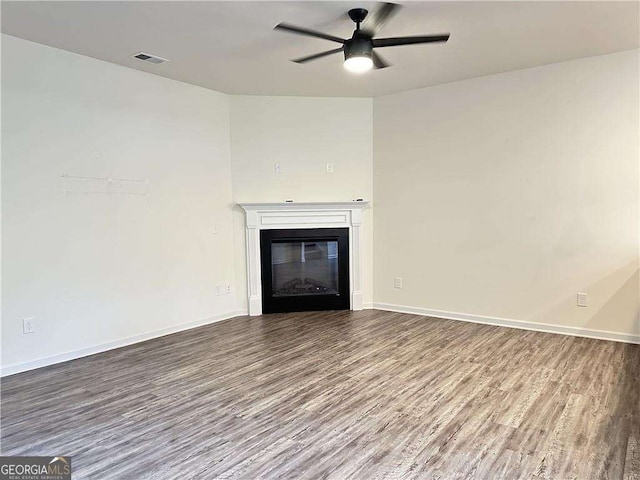 unfurnished living room with wood finished floors, a ceiling fan, a glass covered fireplace, and baseboards