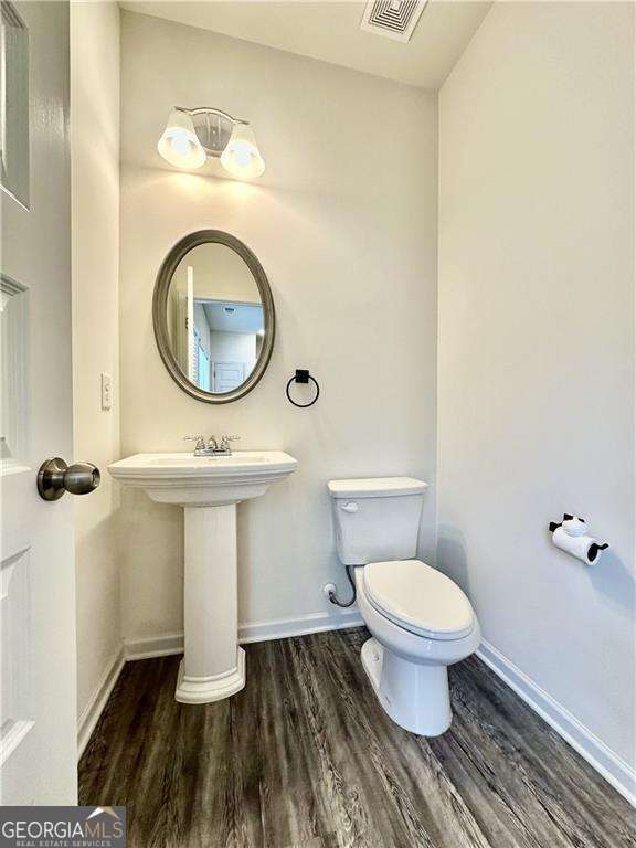 bathroom featuring wood finished floors, toilet, and baseboards