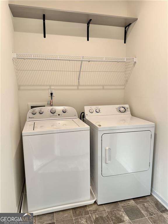 clothes washing area featuring washing machine and clothes dryer and baseboards