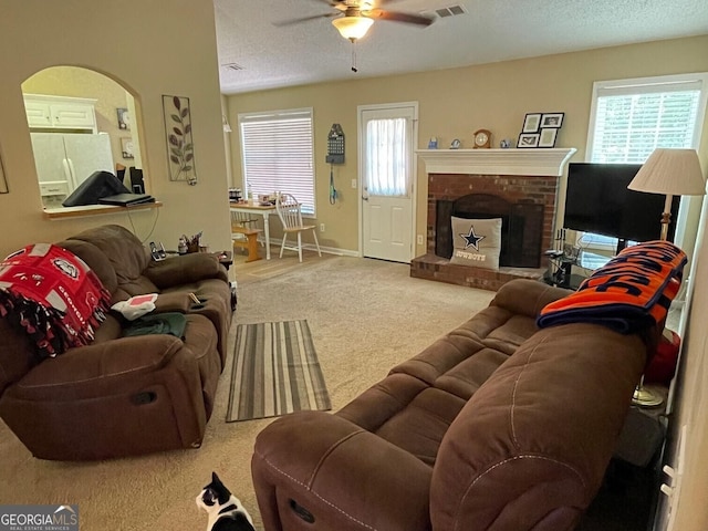 397 E Sycamore Dr, Winder, GA 30680 - carpeted living room featuring a ceiling fan, healthy amount of natural light, a brick fireplace, a textured ceiling, and baseboards