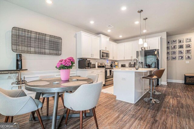 450 Rockfern Ct, Lilburn, GA 30047 - kitchen featuring appliances with stainless steel finishes, white cabinetry, a kitchen island with sink, a kitchen breakfast bar, and recessed lighting