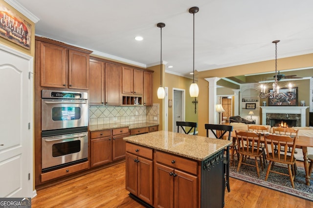 1320 Magnolia Park Cir, Cumming, GA 30040 - kitchen featuring stainless steel double oven, decorative columns, ornamental molding, light wood-type flooring, and decorative light fixtures