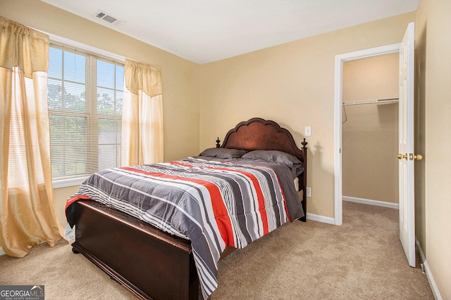 carpeted bedroom featuring baseboards and a walk in closet
