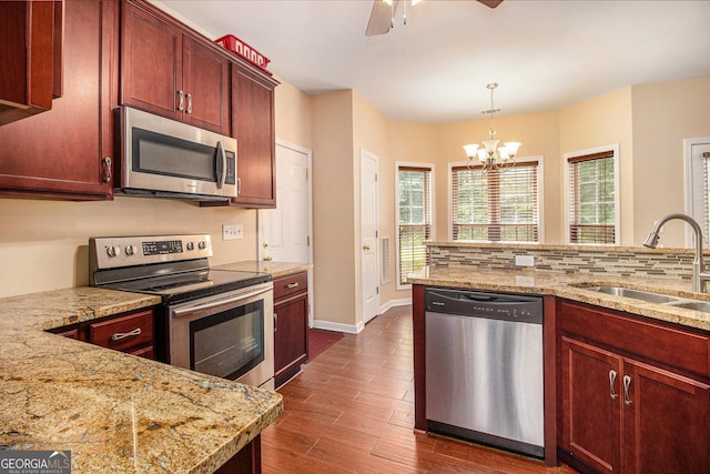 kitchen with stainless steel appliances, a sink, a chandelier, dark wood-style floors, and decorative light fixtures