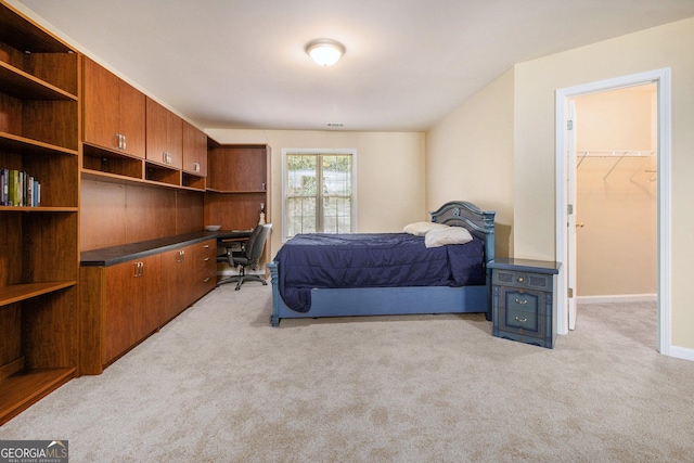 bedroom with light carpet, a spacious closet, and baseboards