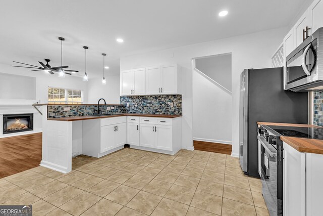 2849 Windsor Forrest Ct, Atlanta, GA 30349 - kitchen featuring electric range, stainless steel microwave, a sink, open floor plan, and butcher block counters