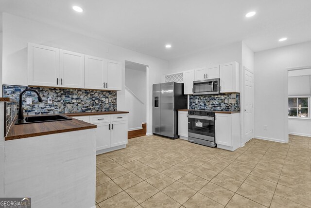 2849 Windsor Forrest Ct, Atlanta, GA 30349 - kitchen featuring stainless steel appliances, wooden counters, a sink, tasteful backsplash, and light tile patterned floors
