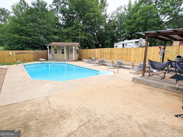 view of pool featuring a fenced backyard, a patio area, an outbuilding, and a wooden deck