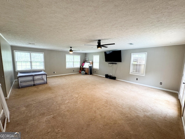 unfurnished living room with a ceiling fan, baseboards, carpet flooring, and a textured ceiling