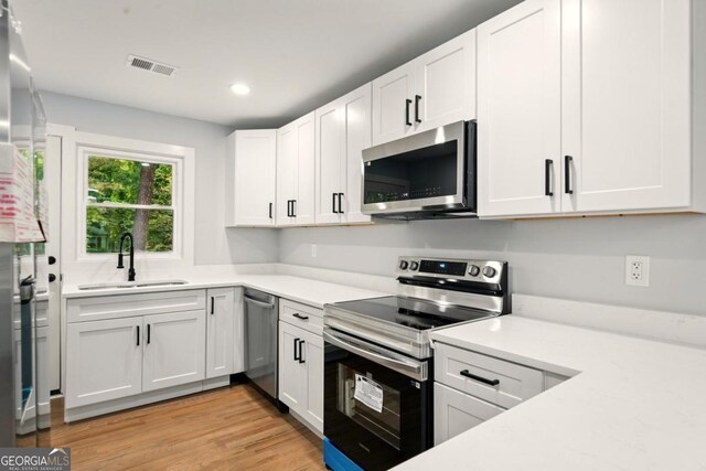 163 Oakcliff Ct, Atlanta, GA 30331 - kitchen featuring appliances with stainless steel finishes, a sink, light countertops, white cabinetry, and light wood finished floors