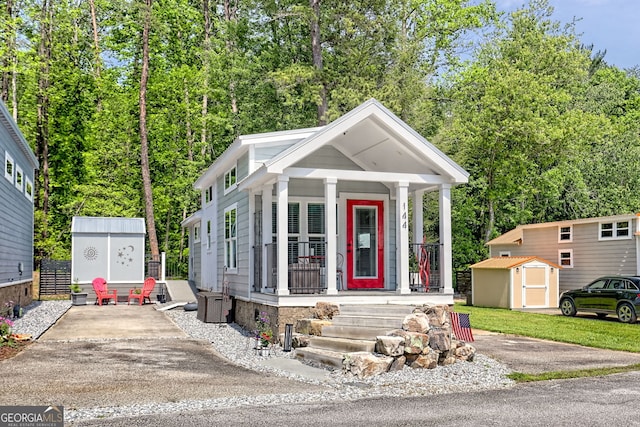 view of front of property with a storage unit, a porch, an outdoor structure, and driveway