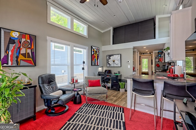 living area featuring a towering ceiling, ceiling fan, healthy amount of natural light, wood finished floors, and wood ceiling