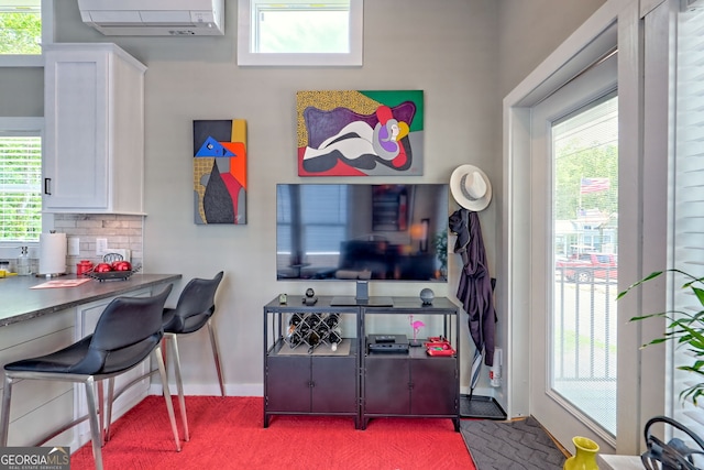 carpeted office with a wall unit AC, plenty of natural light, and baseboards
