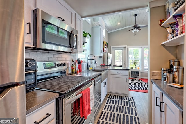 kitchen featuring appliances with stainless steel finishes, tasteful backsplash, a ceiling fan, light wood-type flooring, and white cabinetry