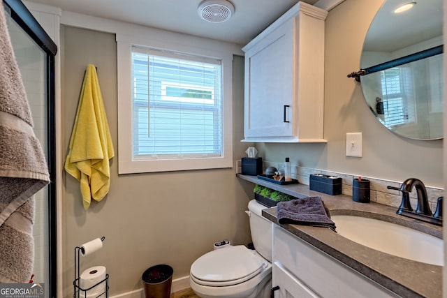 bathroom featuring toilet, vanity, and a shower with shower door