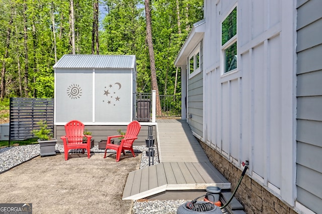 wooden deck featuring a storage unit, an outdoor structure, fence, and a patio