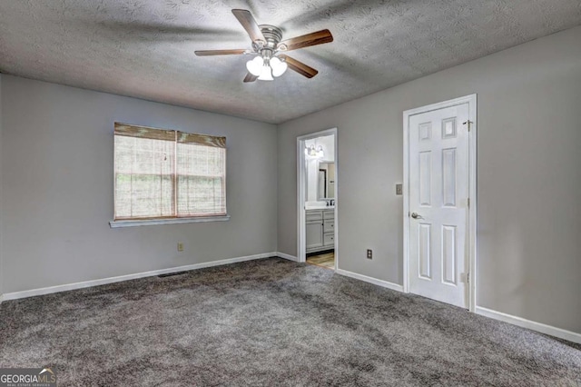unfurnished bedroom featuring carpet, a textured ceiling, connected bathroom, baseboards, and a ceiling fan