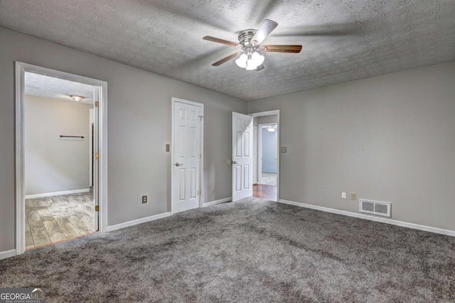 unfurnished bedroom featuring carpet, baseboards, a textured ceiling, and ceiling fan