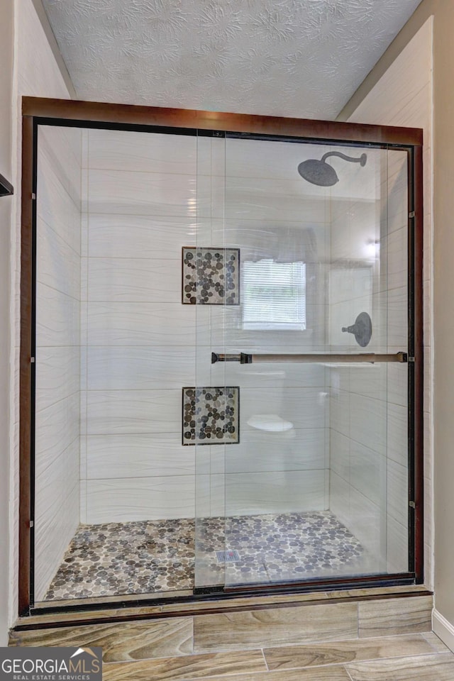 full bath with a shower stall and a textured ceiling