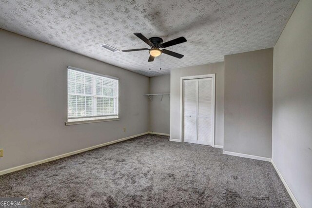 unfurnished bedroom with carpet, a textured ceiling, baseboards, and ceiling fan