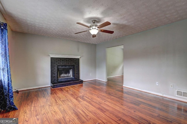 unfurnished living room featuring ceiling fan, wood finished floors, a textured ceiling, baseboards, and a fireplace