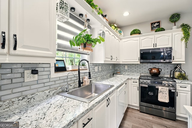 100 Chadwick Pl, Villa Rica, GA 30180 - kitchen with appliances with stainless steel finishes, a sink, white cabinets, backsplash, and light wood-style floors