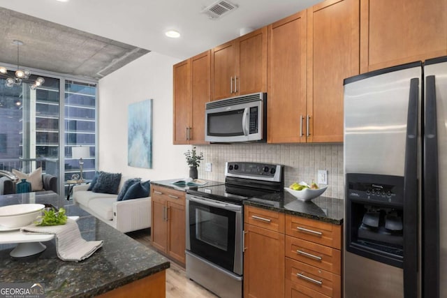 855 Peachtree St NE Unit 1508, Atlanta, GA 30308 - kitchen featuring stainless steel appliances, decorative backsplash, dark stone countertops, light wood-style floors, and brown cabinets