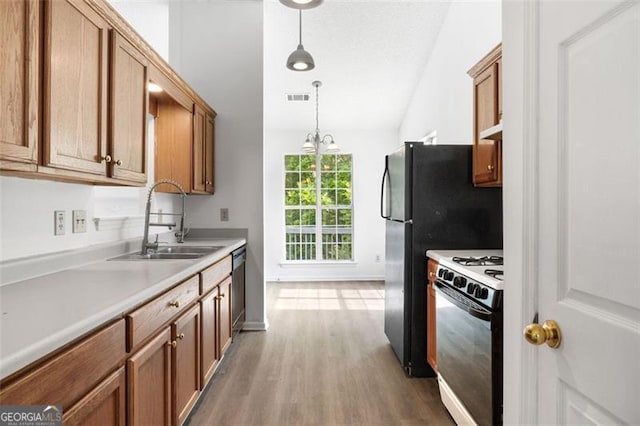 kitchen featuring gas range oven, a sink, brown cabinets, vaulted ceiling, and light countertops