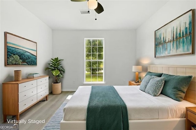 bedroom featuring light wood-style flooring, a ceiling fan, and baseboards