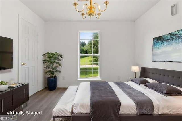 bedroom with a chandelier, wood finished floors, and baseboards