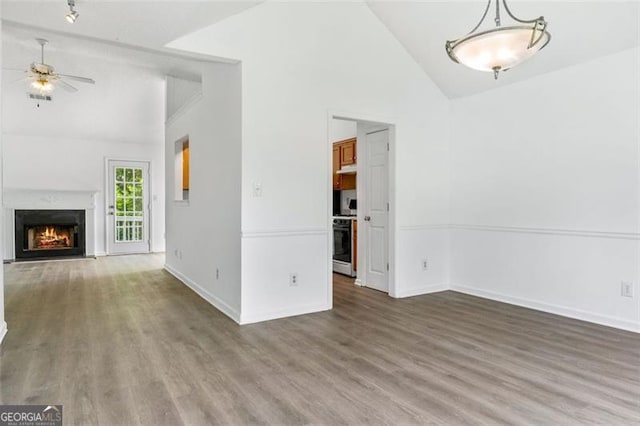 unfurnished living room featuring a ceiling fan, wood finished floors, baseboards, and high vaulted ceiling