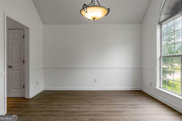 unfurnished room with wood finished floors, lofted ceiling, and baseboards
