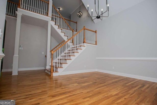 319 Stonebridge Blvd, Bremen, GA 30110 - stairway with wood finished floors, a high ceiling, a chandelier, baseboards, and ornate columns