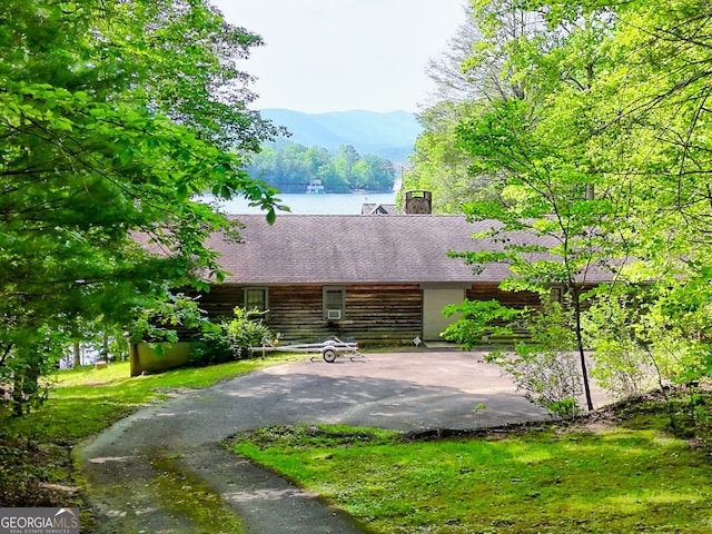 exterior space featuring a shingled roof, a mountain view, log siding, and a chimney
