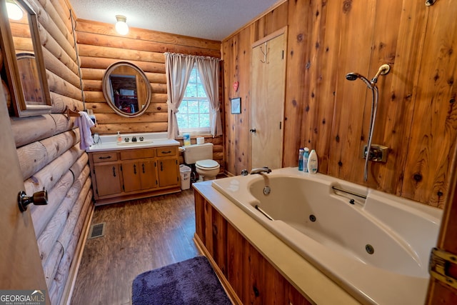 bathroom featuring log walls, a whirlpool tub, a textured ceiling, toilet, and vanity