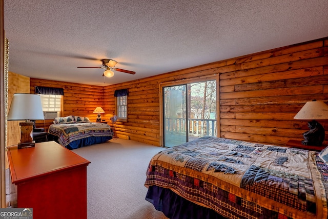 bedroom featuring access to exterior, carpet, a textured ceiling, log walls, and a ceiling fan