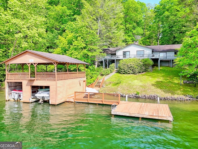 dock area with a water view, a forest view, stairway, and a yard