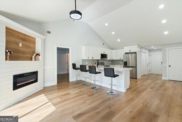162 W Tahoe Dr, Savannah, GA 31405 - kitchen featuring stainless steel appliances, a kitchen bar, a peninsula, white cabinets, and light wood-type flooring