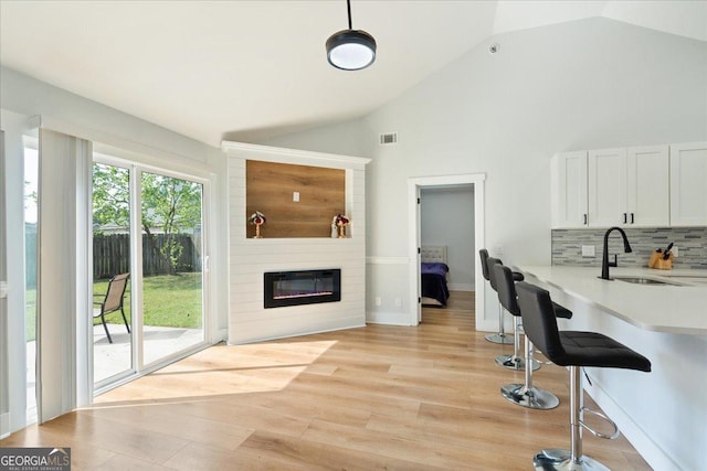 162 W Tahoe Dr, Savannah, GA 31405 - kitchen with light countertops, vaulted ceiling, backsplash, a large fireplace, and white cabinetry
