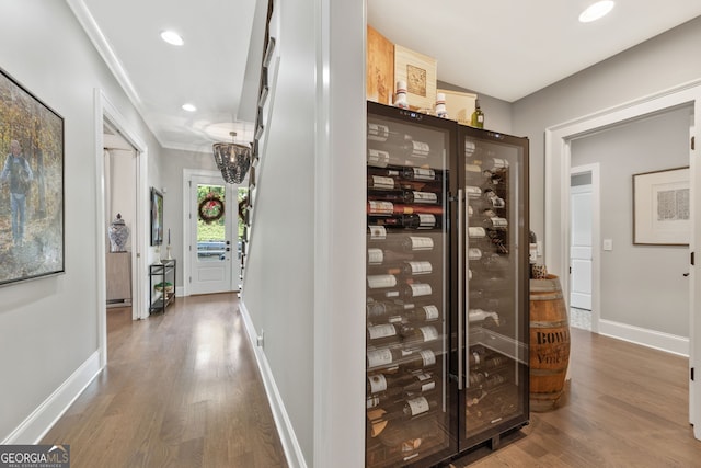 6815 Berkley Rd, Cumming, GA 30040 - wine cellar featuring wood finished floors, crown molding, baseboards, wine cooler, and recessed lighting