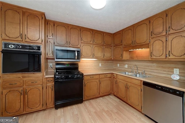1810 King Mill Rd, Mcdonough, GA 30252 - kitchen with black appliances, a sink, light countertops, light wood-style flooring, and brown cabinetry