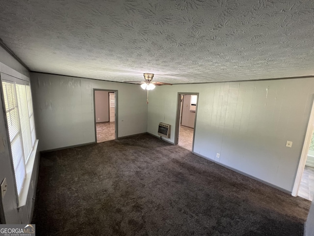 spare room with heating unit, carpet, ceiling fan, and a textured ceiling